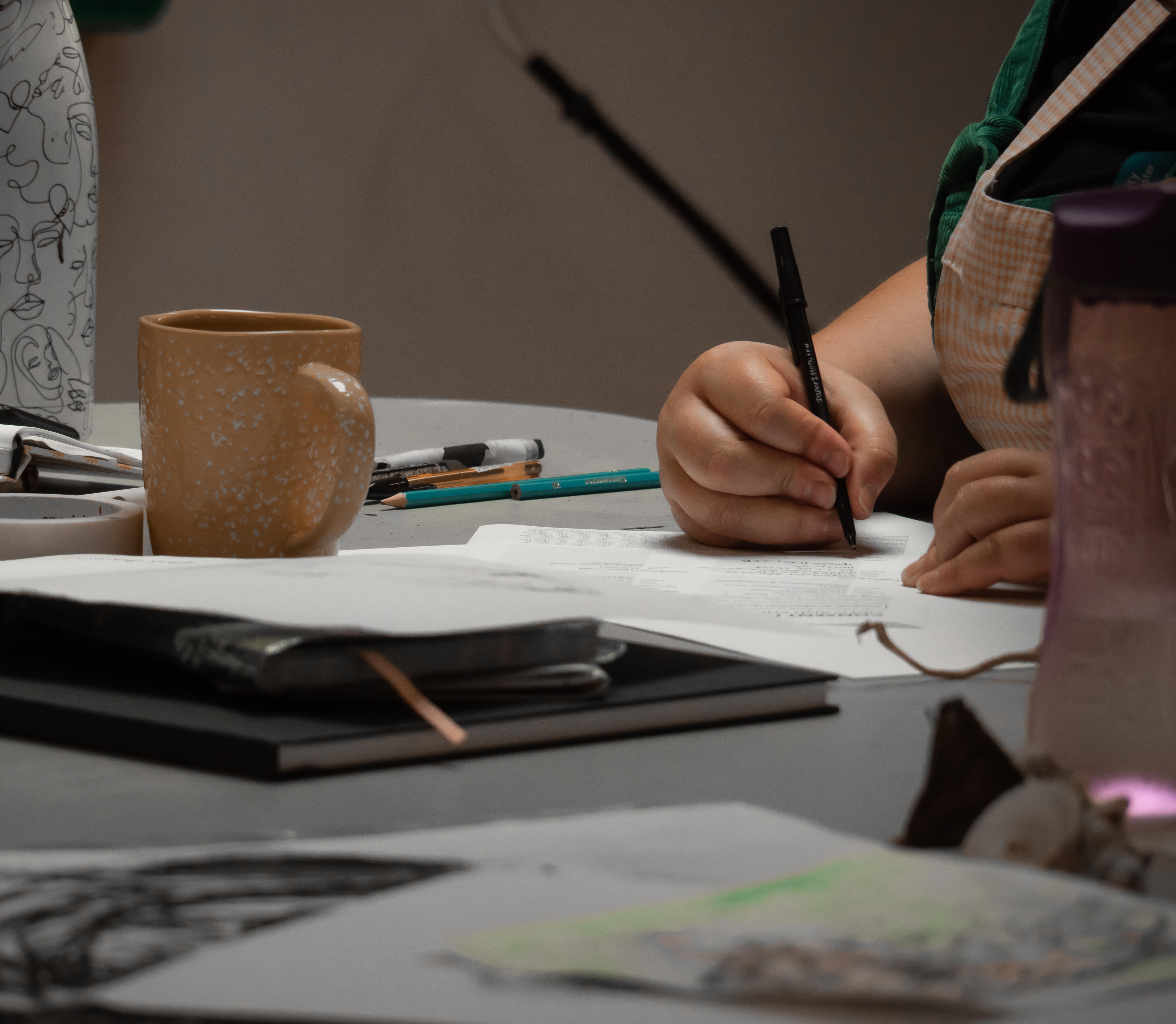 Students writing in notebook on table