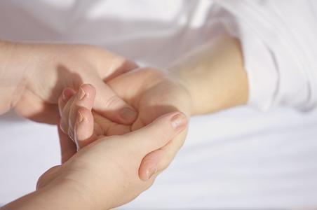 A person is holding another person's palm, with a white background