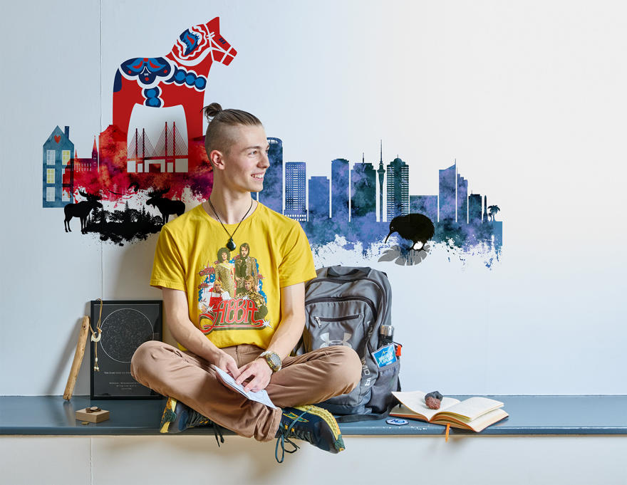 A young person in a yellow Abba top sitting in front of a mural