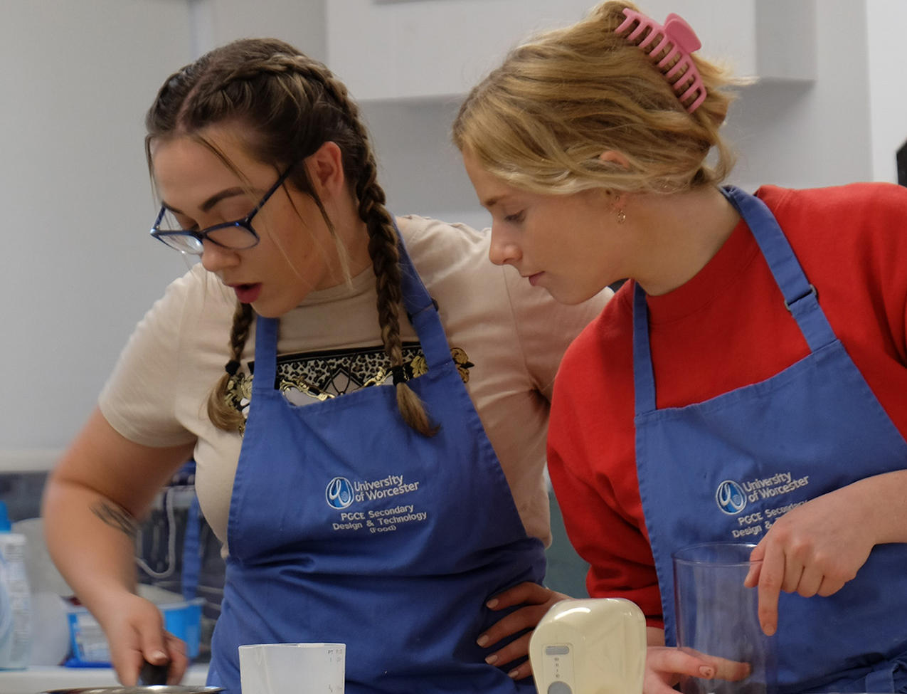 Two students looking at a pot of food cooking