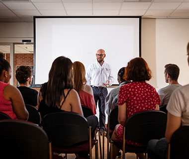 a lecturer is talking to a large group of students in a lecture theatre